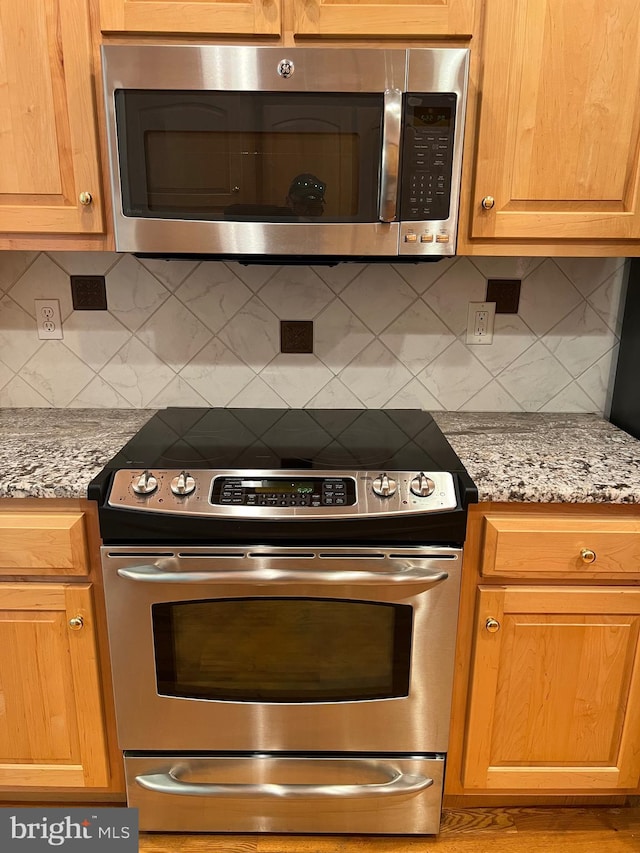 kitchen with light stone countertops, decorative backsplash, and appliances with stainless steel finishes