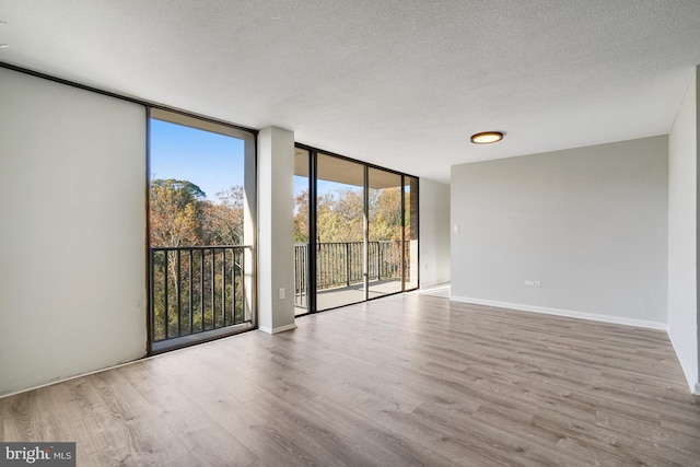 unfurnished room with a textured ceiling, light hardwood / wood-style flooring, and floor to ceiling windows