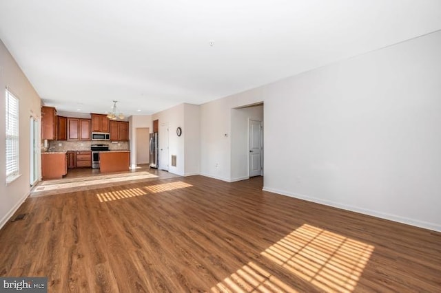 unfurnished living room with dark hardwood / wood-style flooring and a notable chandelier