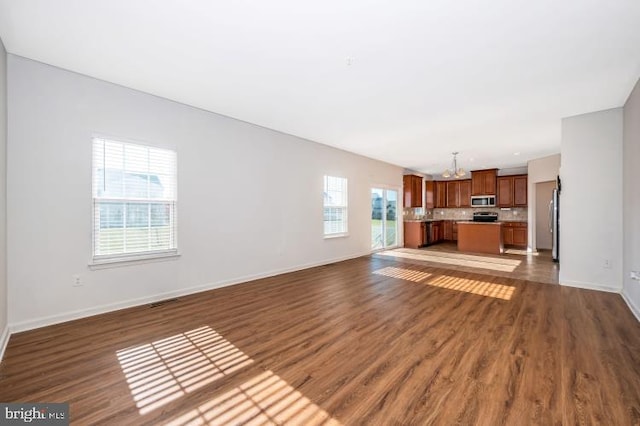 unfurnished living room featuring dark hardwood / wood-style floors and an inviting chandelier