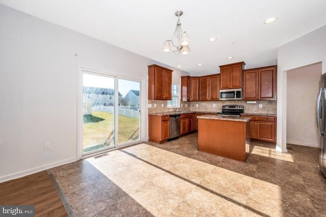 kitchen featuring hanging light fixtures, tasteful backsplash, a kitchen island, stainless steel appliances, and a chandelier