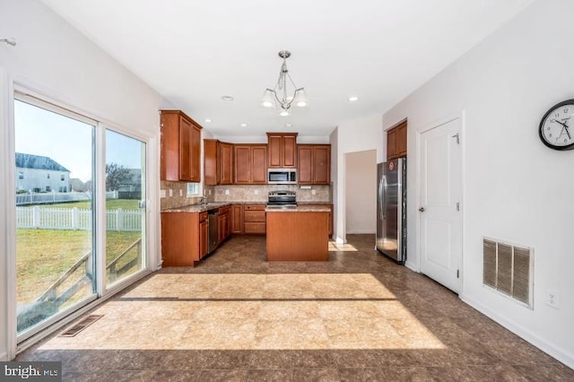 kitchen featuring pendant lighting, a center island, appliances with stainless steel finishes, tasteful backsplash, and a chandelier