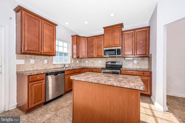 kitchen with a center island, sink, light stone counters, backsplash, and appliances with stainless steel finishes