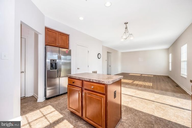 kitchen with decorative light fixtures, stainless steel fridge, light hardwood / wood-style floors, a notable chandelier, and a kitchen island