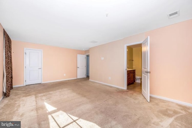 unfurnished bedroom with ensuite bath and light carpet