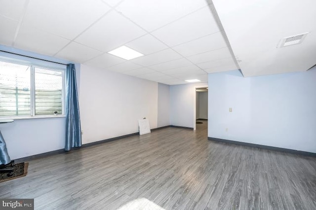 spare room with a paneled ceiling and dark wood-type flooring