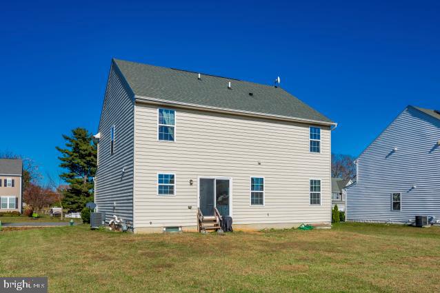 rear view of house with a lawn and cooling unit