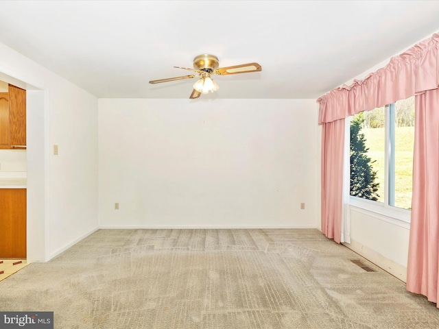 spare room featuring light carpet and ceiling fan