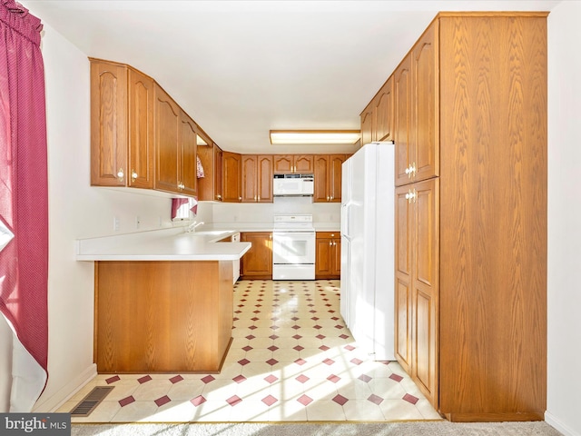 kitchen featuring white appliances, kitchen peninsula, and sink