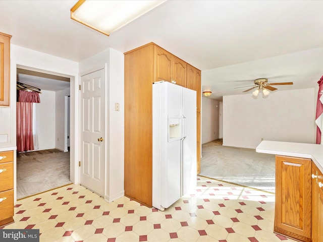 kitchen featuring ceiling fan, light colored carpet, and white refrigerator with ice dispenser