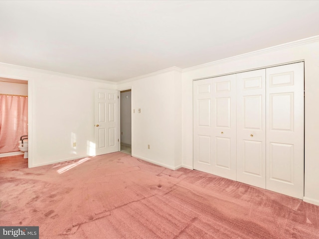 unfurnished bedroom with crown molding, carpet floors, ensuite bath, and a closet