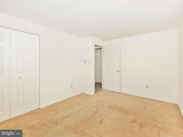 unfurnished bedroom with light colored carpet and a closet