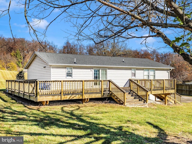 rear view of property with a wooden deck and a lawn