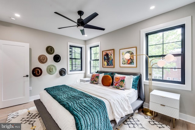 bedroom with multiple windows, hardwood / wood-style flooring, and ceiling fan