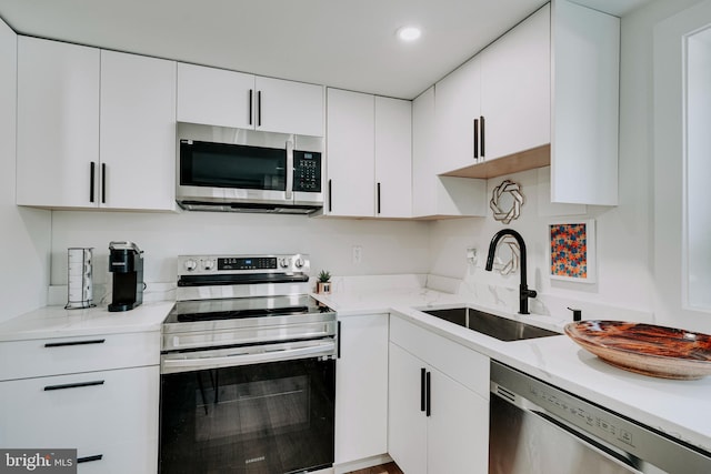 kitchen with light stone countertops, white cabinets, sink, and stainless steel appliances