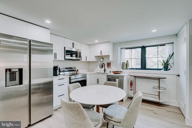 kitchen featuring white cabinets, sink, light wood-type flooring, and appliances with stainless steel finishes