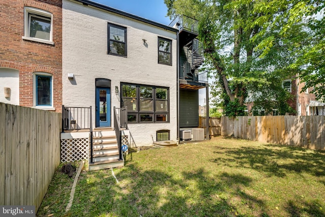 rear view of house featuring central AC unit, a yard, and a balcony