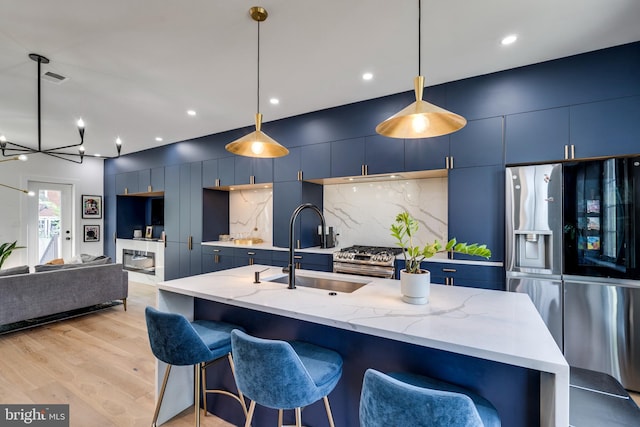 kitchen with sink, blue cabinets, appliances with stainless steel finishes, and decorative light fixtures