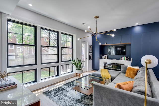 living room featuring light hardwood / wood-style floors, a notable chandelier, and a high end fireplace