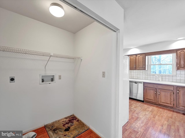 washroom with sink, hookup for a washing machine, light wood-type flooring, and hookup for an electric dryer