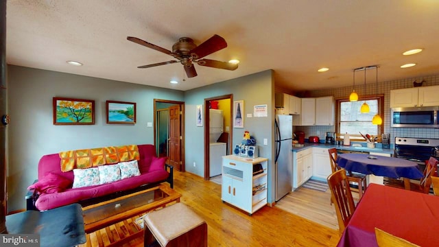 kitchen with stainless steel appliances, light hardwood / wood-style floors, tasteful backsplash, white cabinets, and pendant lighting