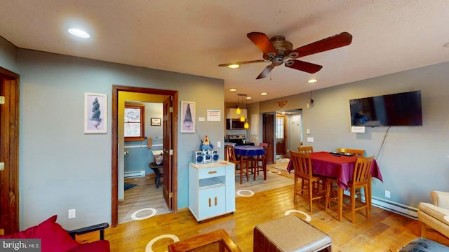 living room with ceiling fan, light hardwood / wood-style flooring, and a baseboard heating unit