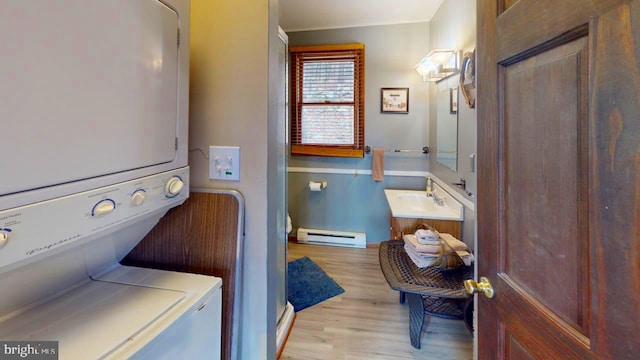 laundry room featuring a baseboard heating unit, stacked washer and dryer, sink, and light wood-type flooring