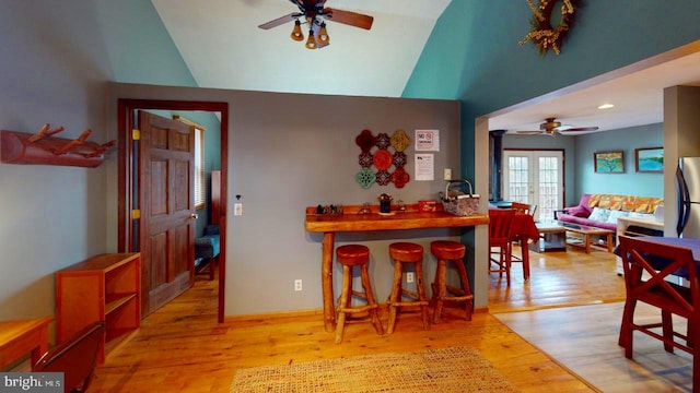 dining area featuring french doors, light wood-type flooring, and lofted ceiling