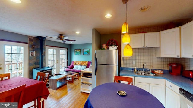 kitchen with tasteful backsplash, stainless steel appliances, light wood-type flooring, sink, and white cabinets