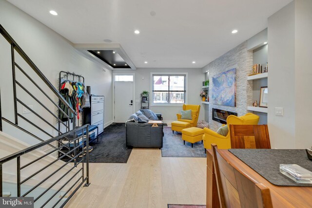 living room with a stone fireplace and light wood-type flooring