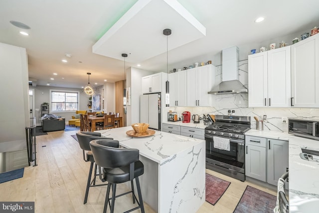 kitchen featuring white cabinetry, light hardwood / wood-style flooring, wall chimney exhaust hood, and stainless steel appliances