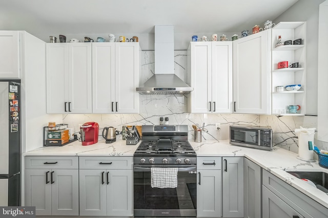 kitchen with white cabinetry, light stone counters, wall chimney exhaust hood, and appliances with stainless steel finishes