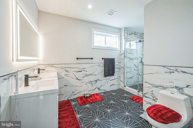 bathroom featuring vanity, a shower with door, tile patterned flooring, toilet, and tile walls