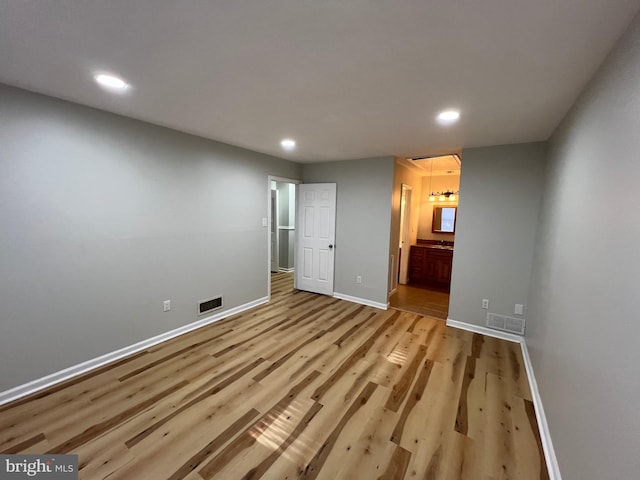 unfurnished bedroom featuring ensuite bath and light hardwood / wood-style floors