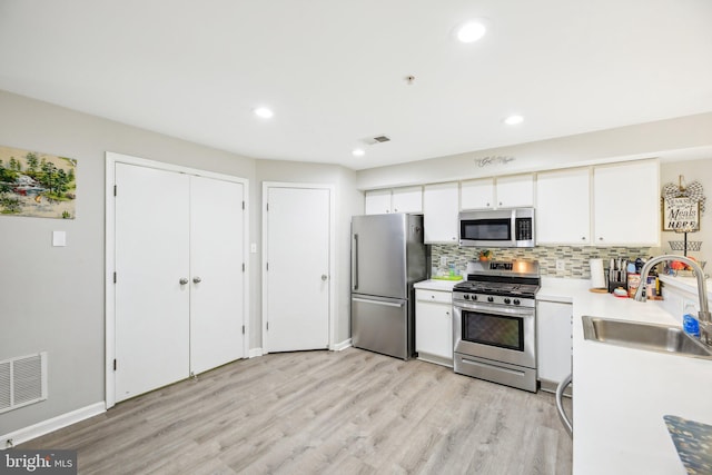 kitchen with white cabinetry, light wood-type flooring, stainless steel appliances, and sink