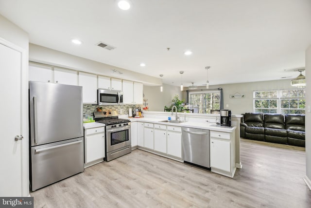 kitchen featuring white cabinetry, stainless steel appliances, sink, and decorative light fixtures