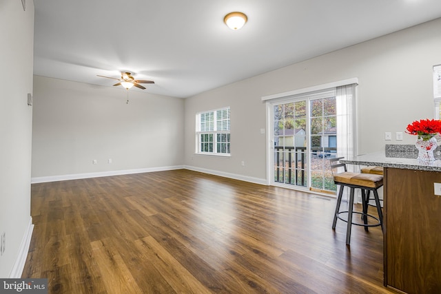 living room featuring dark wood-type flooring and ceiling fan