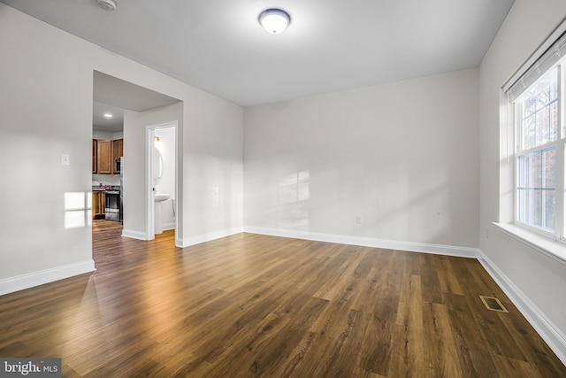 spare room featuring a wealth of natural light and dark wood-type flooring