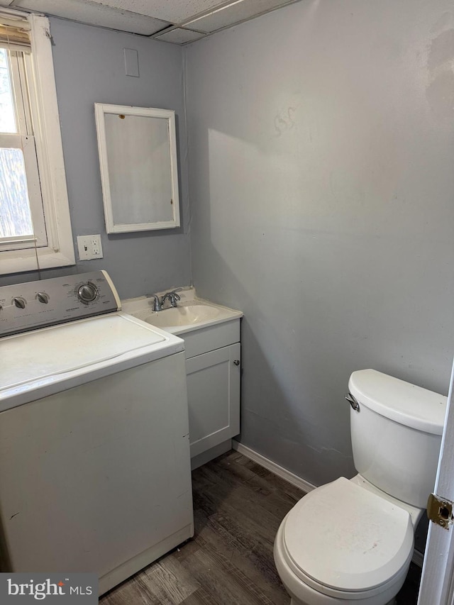 bathroom with hardwood / wood-style flooring, a drop ceiling, washer / clothes dryer, vanity, and toilet