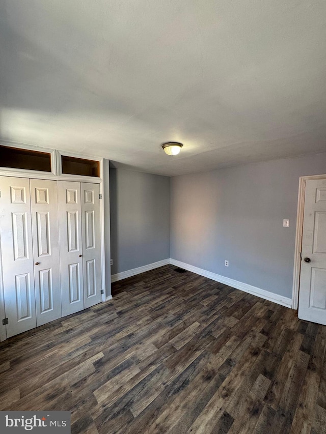 unfurnished bedroom featuring dark hardwood / wood-style flooring and a closet