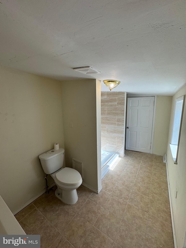 bathroom featuring tile patterned flooring, a textured ceiling, and toilet