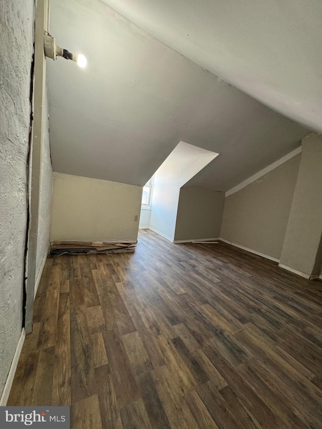 additional living space with dark wood-type flooring and vaulted ceiling