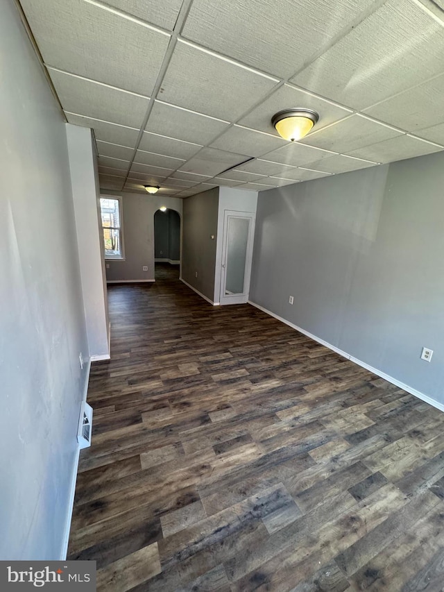 empty room featuring a drop ceiling and dark wood-type flooring