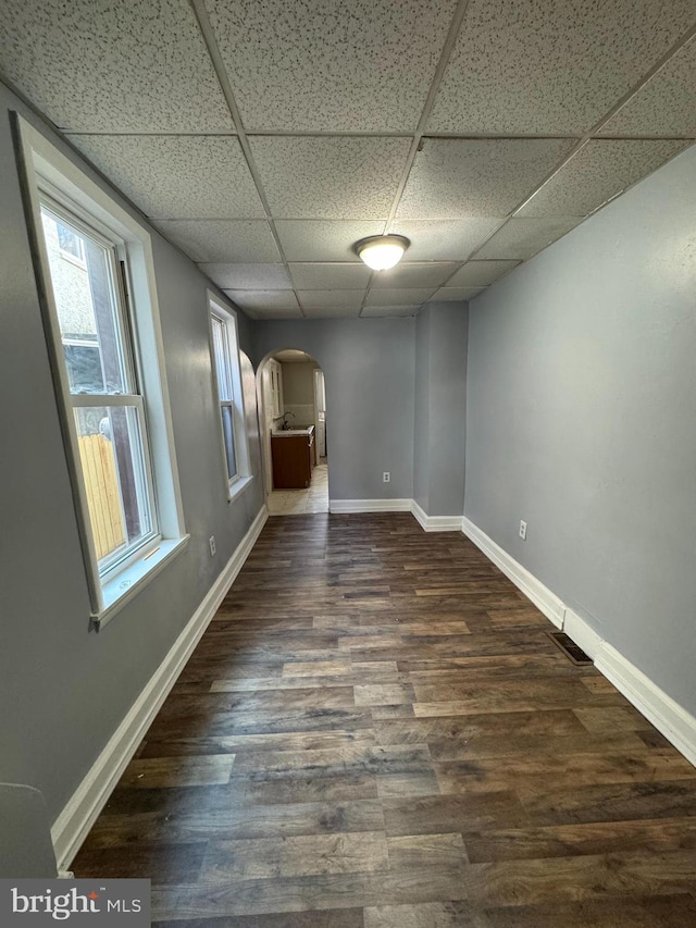 empty room with a paneled ceiling and dark wood-type flooring