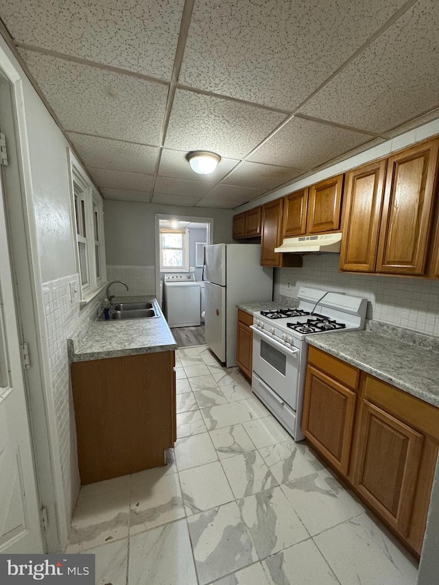 kitchen featuring washer / clothes dryer, a paneled ceiling, white appliances, and sink