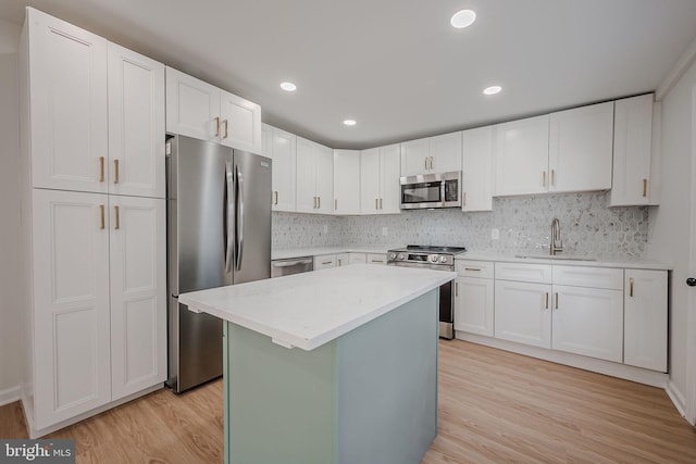 kitchen featuring a center island, sink, stainless steel appliances, white cabinets, and light wood-type flooring