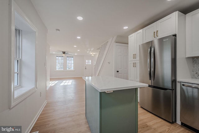 kitchen featuring a center island, ceiling fan, light wood-type flooring, white cabinetry, and stainless steel appliances