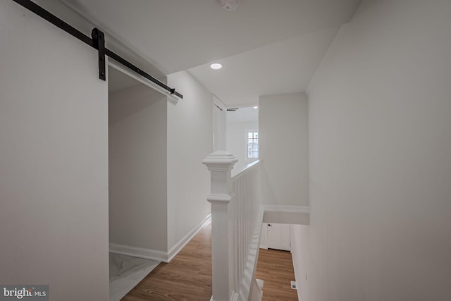 walk in closet featuring a barn door and light hardwood / wood-style flooring