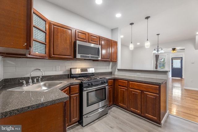 kitchen with sink, light hardwood / wood-style flooring, appliances with stainless steel finishes, decorative light fixtures, and kitchen peninsula