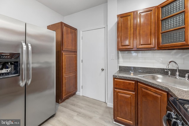 kitchen featuring sink, tasteful backsplash, stainless steel fridge with ice dispenser, light hardwood / wood-style floors, and range